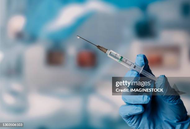 gloved hand holding a syringe - shot stockfoto's en -beelden