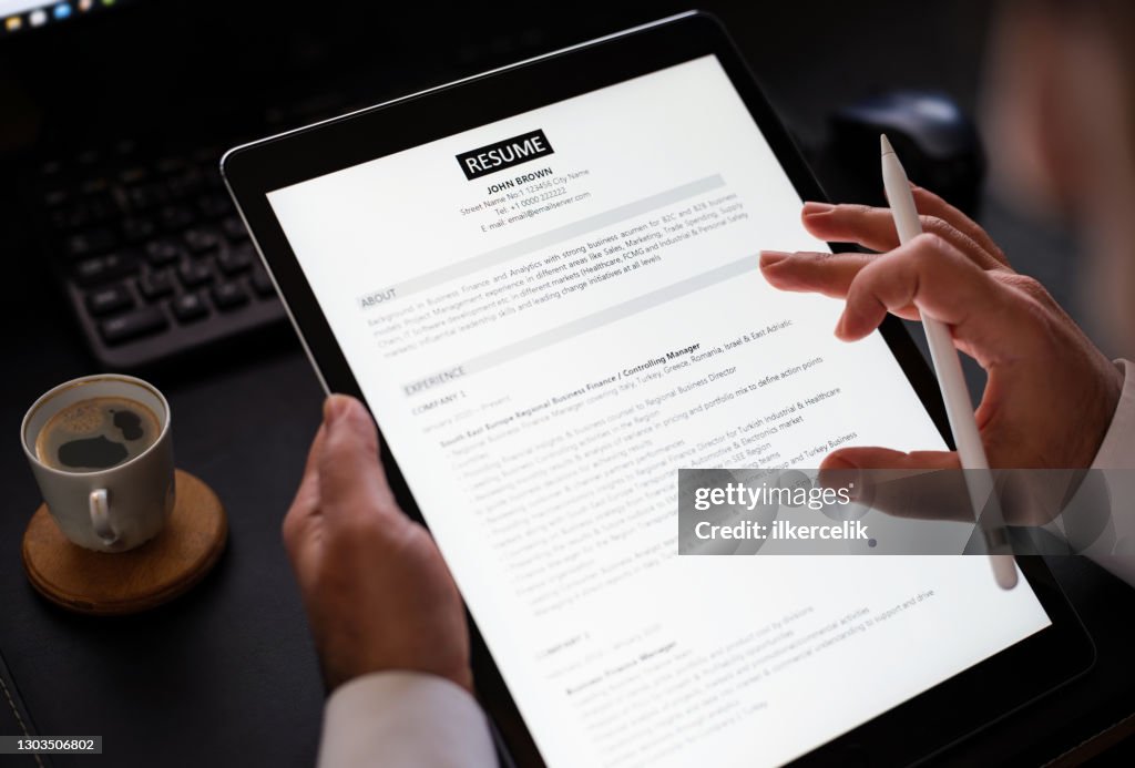 Geschäftsmann liest einen Lebenslauf auf digitalem Tablet, um richtiges Personal einzustellen