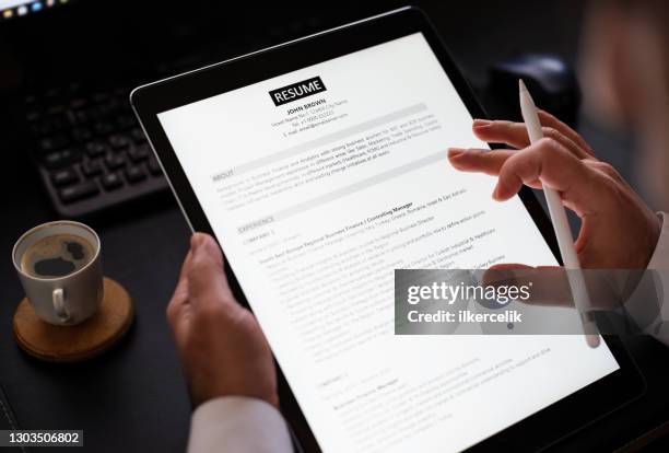 geschäftsmann liest einen lebenslauf auf digitalem tablet, um richtiges personal einzustellen - bewerbungsformular stock-fotos und bilder