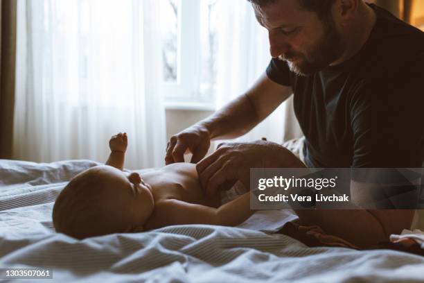 middle age caucasian father changing diaper for newborn baby daughter. male man parent taking care of child at home alone. authentic lifestyle candid moment. single dad family life concept. - nappy change stockfoto's en -beelden