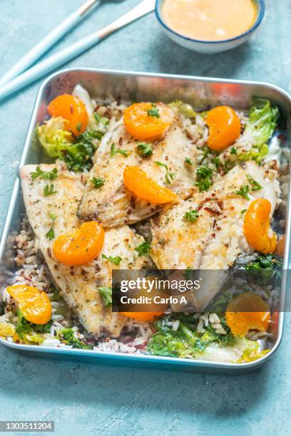 baked fish fillet  with rice  tangerines and kale - cod dinner stock pictures, royalty-free photos & images