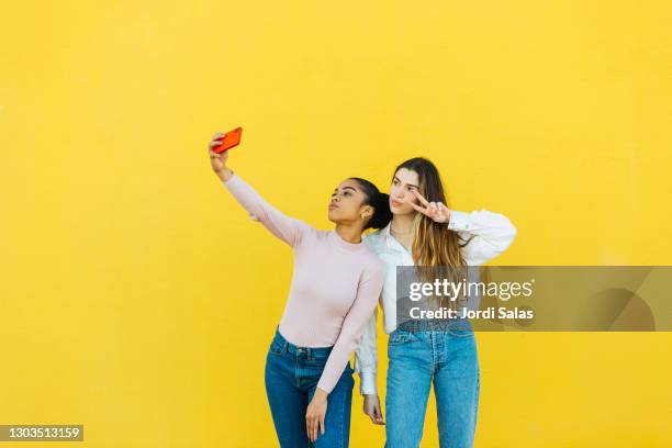 portrait of two young girls taking a selfie - two people plain background stock pictures, royalty-free photos & images