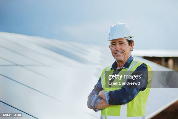 een midden oude mens die met zonnepaneel, zonne-energie werkt - building contractor stockfoto's en -beelden