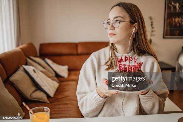 ritratto di una giovane donna nostalgica che tiene la torta di compleanno - sad birthday foto e immagini stock