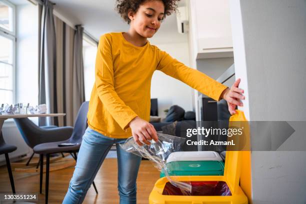 mixed race girl recycling plastic and throwing it into a garbage bin - mixed recycling bin stock pictures, royalty-free photos & images
