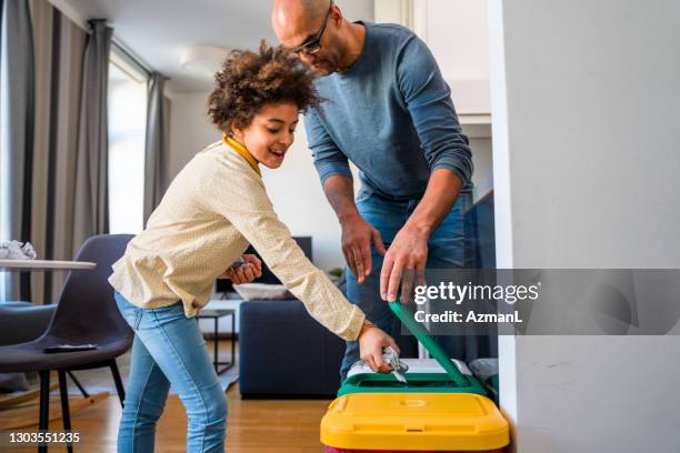 mixed race father and daughter recycling paper and throwing it into a garbage bin - recycling bins stock pictures, royalty-free photos & images