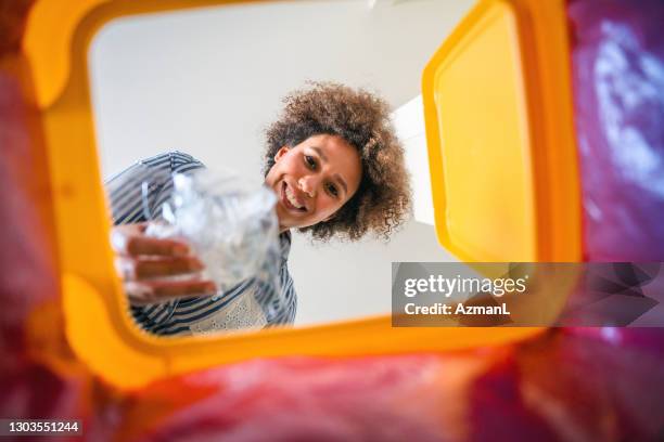 raza mixta mediana mujer adulta reciclando plástico visto desde el interior de cubo de basura - bin fotografías e imágenes de stock