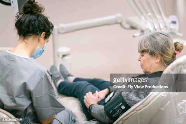 hogere vrouwelijke patiënt die bloeddruk tijdens tandafspraak heeft genomen - medicaid stockfoto's en -beelden
