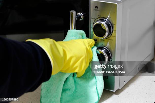 close-up of hand with rubber glove cleaning microwaves - microwave stock pictures, royalty-free photos & images