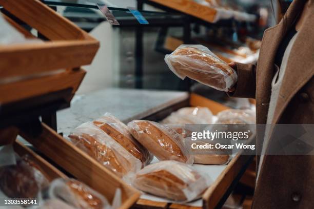 cropped shot of young woman shopping freshly made bread in a bakery shop - pan fotografías e imágenes de stock