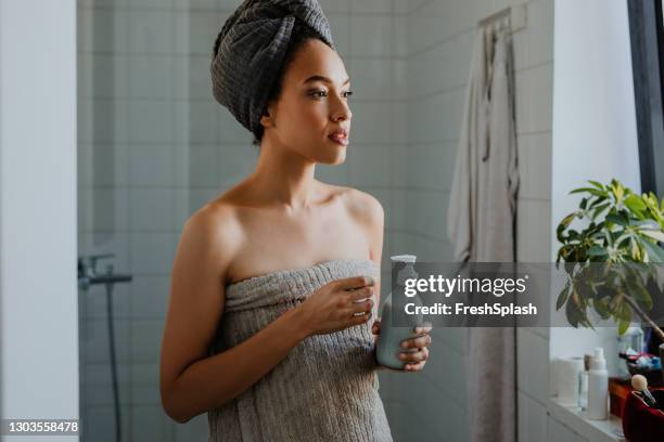 mooie afro vrouw die zich in de vloeibare zeep van de badkamersholding bevindt - facial cleanser stockfoto's en -beelden