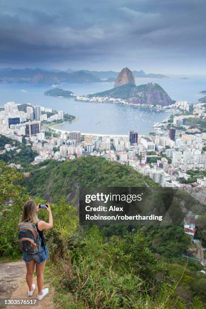 a female hiker looking out over the landscape of rio to sugar loaf mountain from tijuca national park, rio de janeiro, brazil, south america - sugar loaf bildbanksfoton och bilder