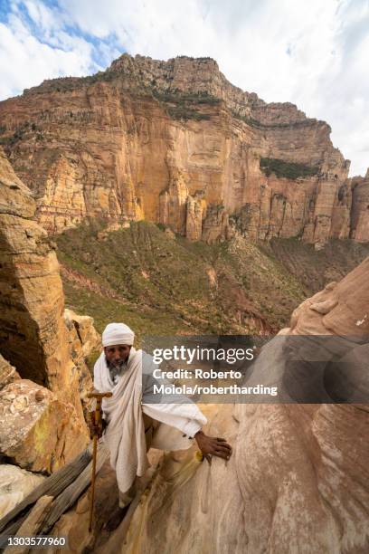 ethiopian priest leaning on steep rocks leading to abuna yemata guh church, gheralta mountains, tigray region, ethiopia, africa - abuna yemata guh church stock pictures, royalty-free photos & images