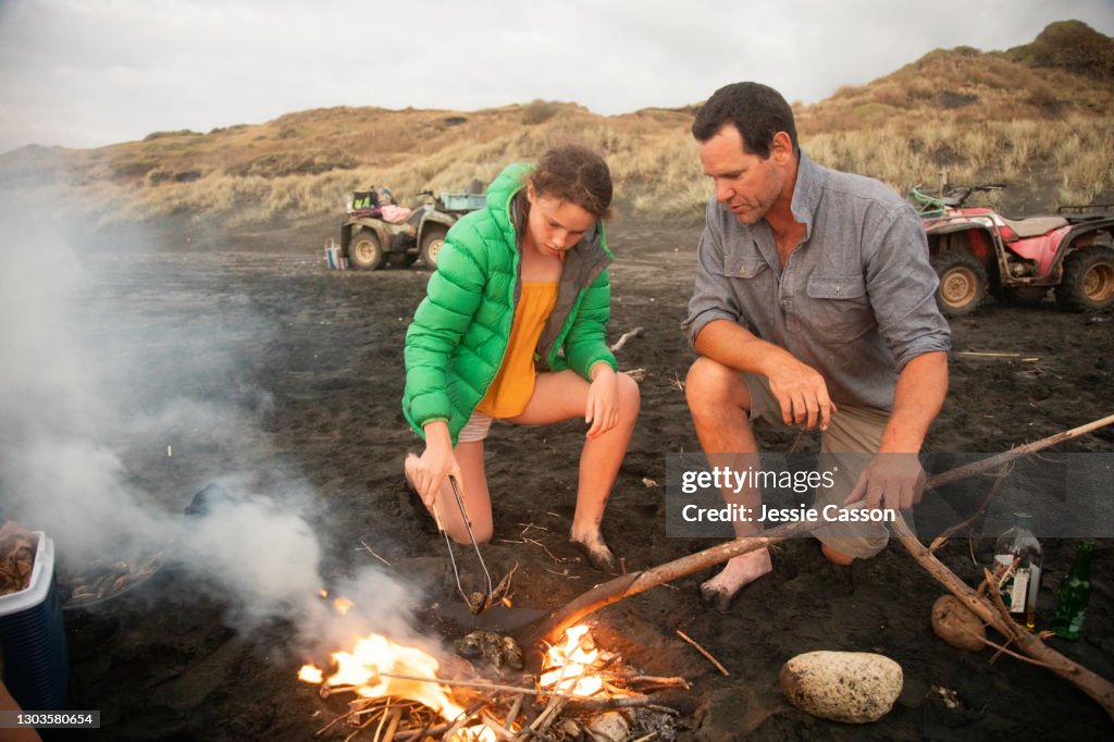 Father and daughter building fire at beach