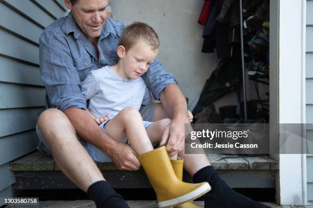 father helping son put on boots - child getting dressed stock pictures, royalty-free photos & images