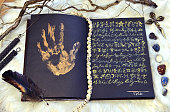 Sell soul to devil concept, black magic book with palmprint and quill.