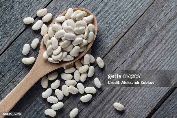 dry red beans on a wooden spoon and on a blue ceramic plate, on the background of the table. vegetarian and vegan food. - bean stock pictures, royalty-free photos & images