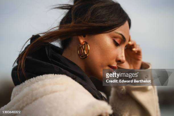 Patricia Gloria Contreras wears golden Vuitton earrings, a black hoodie sweater from Mr & Mrs Italy, on February 20, 2021 in Paris, France.