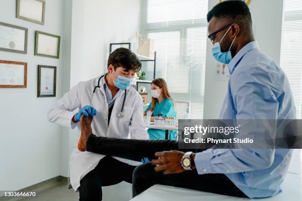 man having an appointment with her doctor for leg pain - black men feet stock pictures, royalty-free photos & images