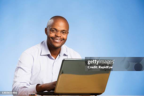 handsome man looks contented and serene as he works at his laptop computer - pleased face laptop stock pictures, royalty-free photos & images