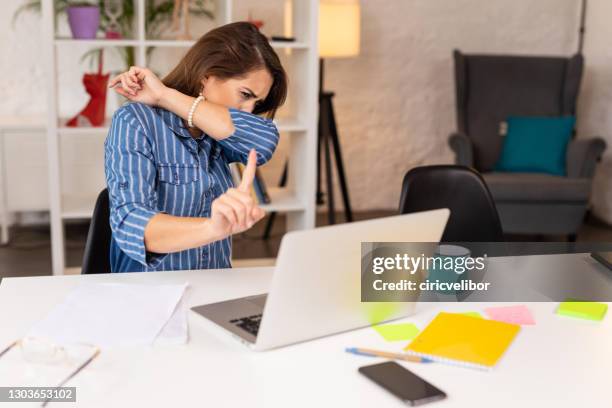 woman coughing into elbow while having a video call in home office - covering cough stock pictures, royalty-free photos & images