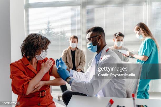 women with face mask getting vaccinated, coronavirus, covid-19 and vaccination concept - medical research group stock pictures, royalty-free photos & images