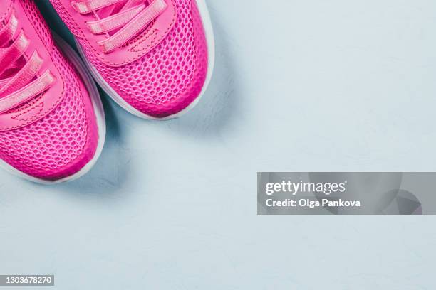 bright pink sneakers in flat style on light blue background. close-up, top view, copyspace. discounts, sales, shopping, storage of shoes concept.  sport, healthy lifestyle, activity motion, running concept. - pink sneakers fotografías e imágenes de stock