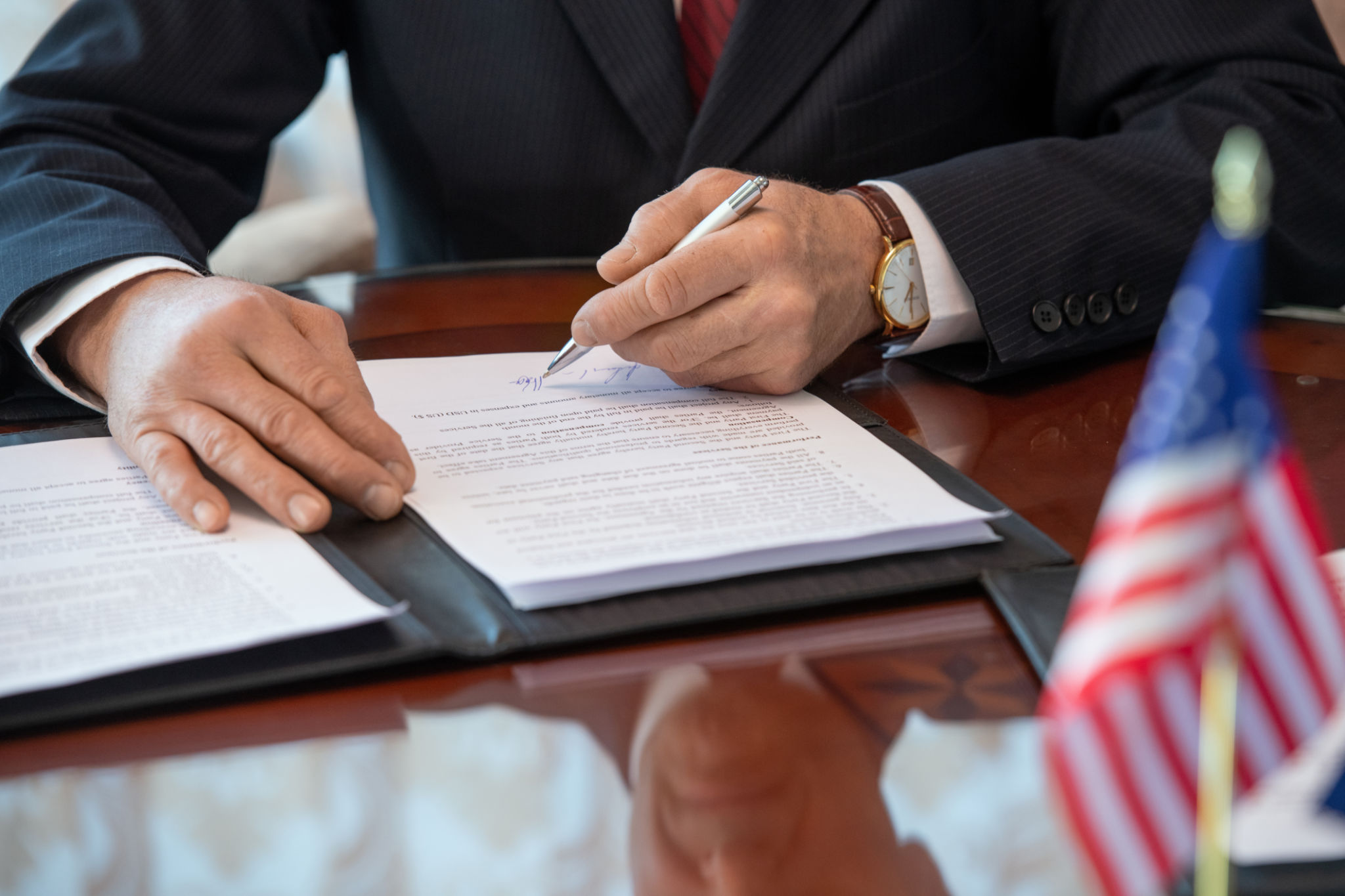 Hands of mature American delegate in formalwear pointing at signature in contract Hands of mature American delegate in formalwear pointing at signature in contract
