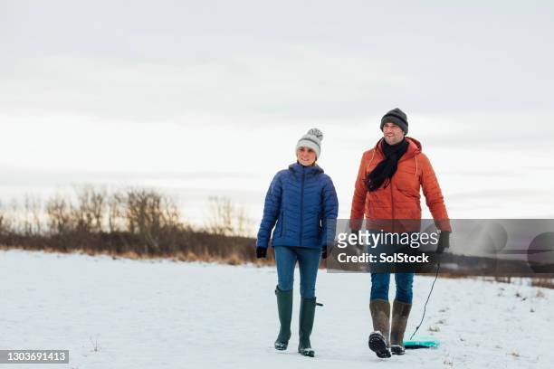 mature couple walking in the snow - mature couple winter outdoors stock pictures, royalty-free photos & images