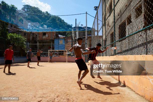 five young men playing soccer on a clay court - favela stock-fotos und bilder