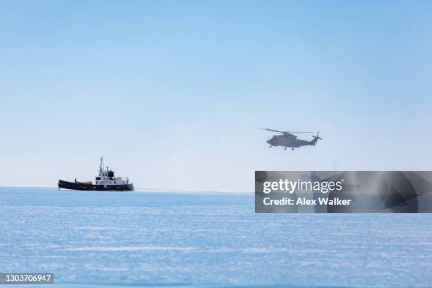 military helicopter hovering low next to ships. - nautische ausrüstung stock-fotos und bilder