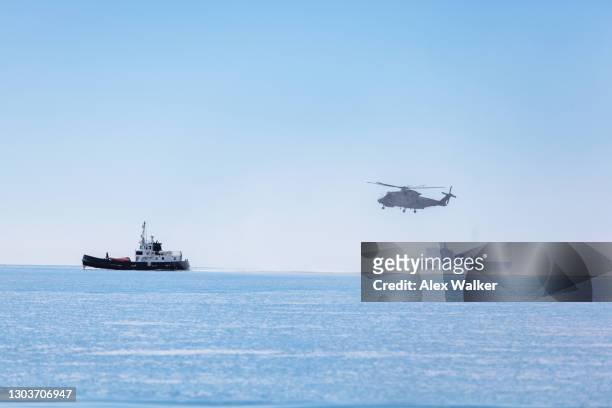 military helicopter hovering low next to ships. - verboten stockfoto's en -beelden