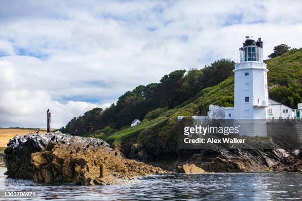 white lighthouse with rocks and green fields in idyllic location - falmouth england stock-fotos und bilder