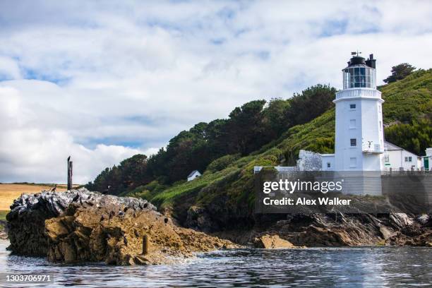 white lighthouse with rocks and green fields in idyllic location - falmouth england stock pictures, royalty-free photos & images