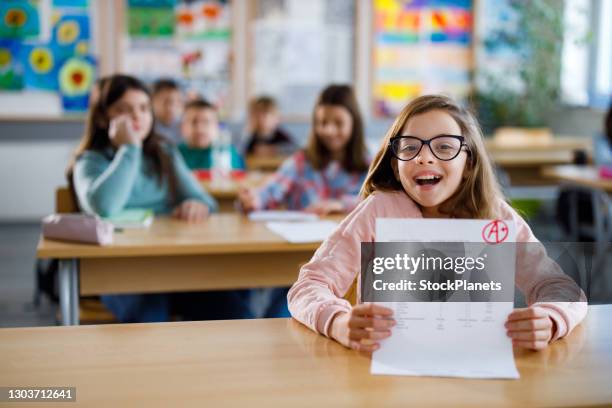 happy schoolgirl showing her a grade on a test at elementary school - child report card stock pictures, royalty-free photos & images