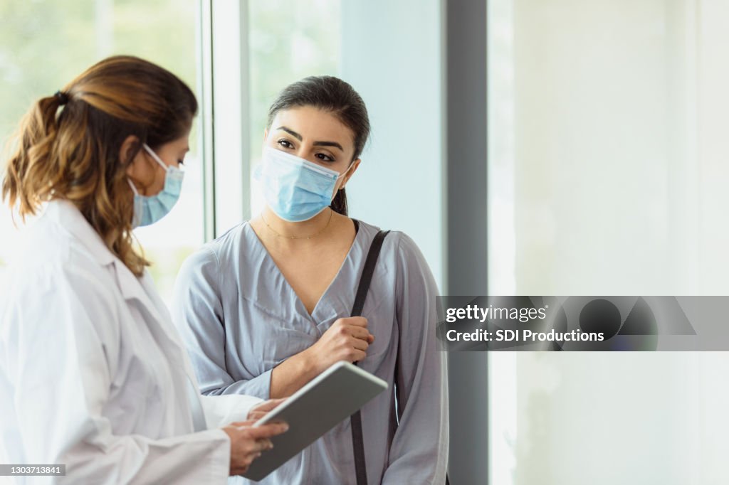 Female gynecologist shares information on digital tablet with patient