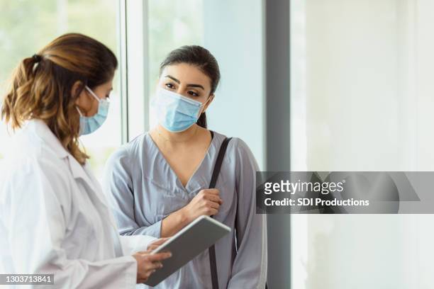 female gynecologist shares information on digital tablet with patient - protective face mask stock pictures, royalty-free photos & images