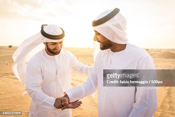 two arabic men together in desert,dubai,united arab emirates - gulf countries stock-fotos und bilder