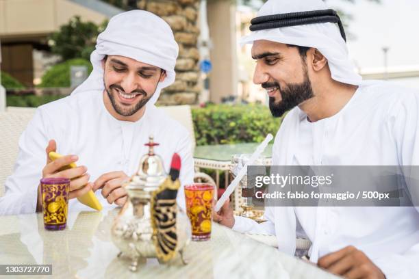 two arab men talking in a city with mobile phone,dubai,united arab emirates - middle east friends stock pictures, royalty-free photos & images