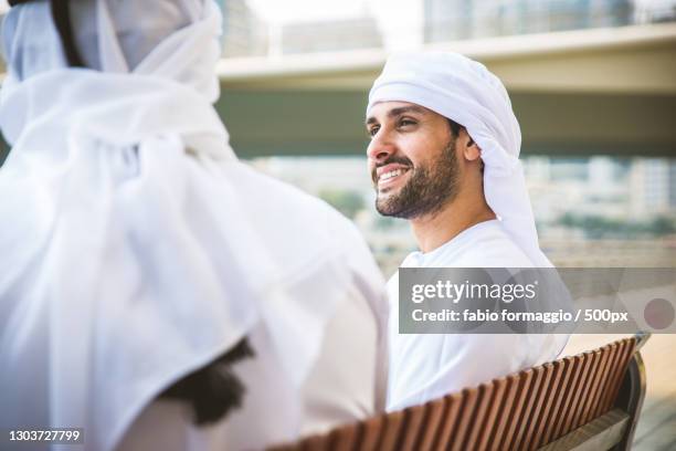 two arab business men sitting together outside on bench,dubai,united arab emirates - middle east friends stock pictures, royalty-free photos & images