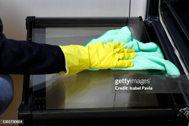 close-up of hand with rubber glove cleaning oven with rag - oven stock pictures, royalty-free photos & images