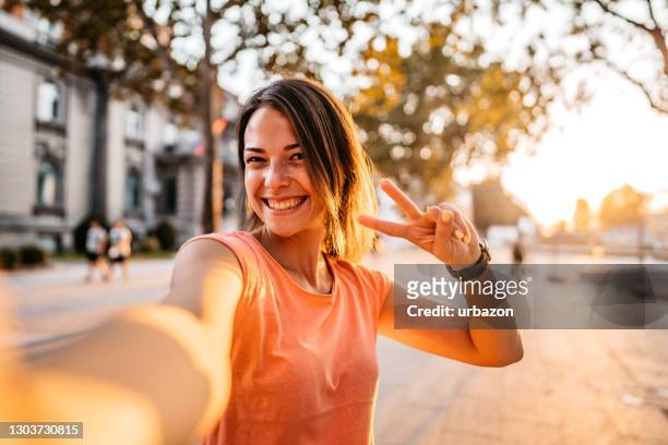 lächelnde frau macht selfie - victory sign stock-fotos und bilder