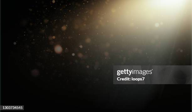 blurred particles in the orange light beam over black background - string lights on black stock illustrations