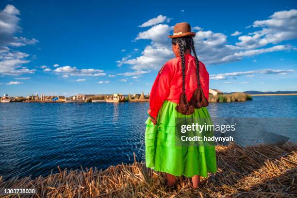 peruanische frau mit blick auf die schwimmende insel uros, tititcaca-see - uros inseln stock-fotos und bilder