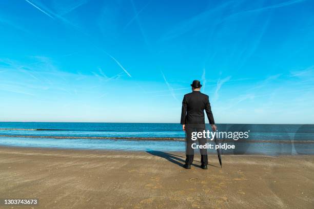 engländer am strand stehend, mit blick auf das meer - melone hut stock-fotos und bilder