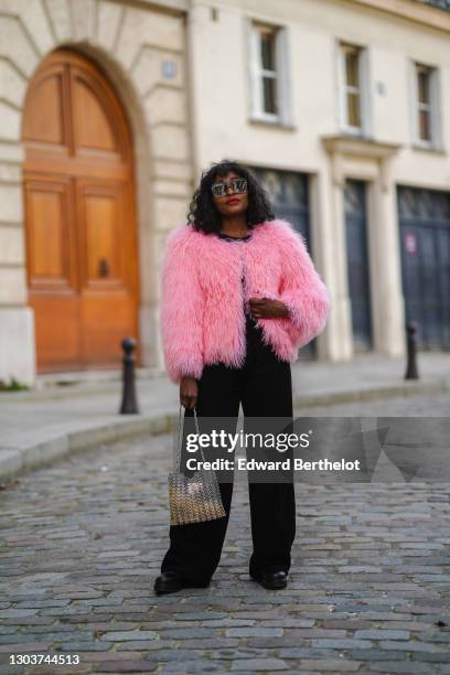 Carrole Sagba aka Linaose wears sunglasses from Gigi Studio, a pink fluffy winter coat from Anina, a t-shirt from Uniqlo, black flared pants from...