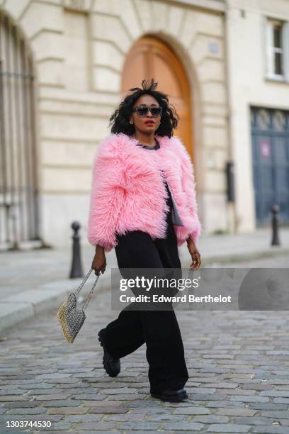 Carrole Sagba aka Linaose wears sunglasses from Gigi Studio, a pink fluffy winter coat from Anina, a t-shirt from Uniqlo, black flared pants from...