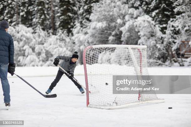 shooting the hockey puck at an open net on an outdoor ice rink - hockey puck in net stock pictures, royalty-free photos & images