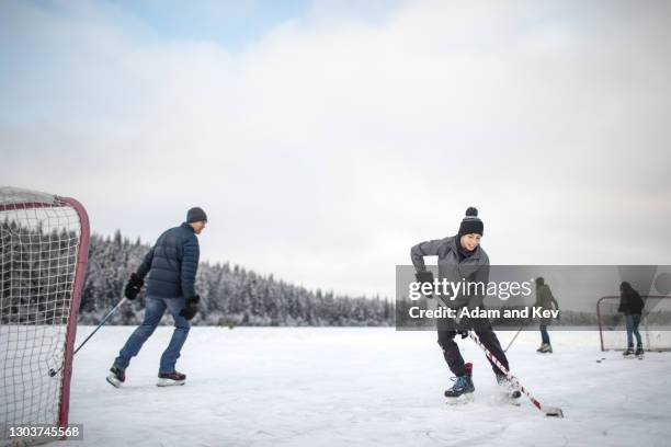 playing hockey on outdoor ice rink - hockey player foto e immagini stock