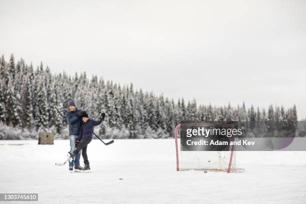 ice-hockey players hug in celebration on outdoor ice-rink - outdoor ice hockey stock pictures, royalty-free photos & images